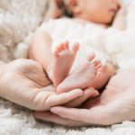 新生児の足に手を添える両親
