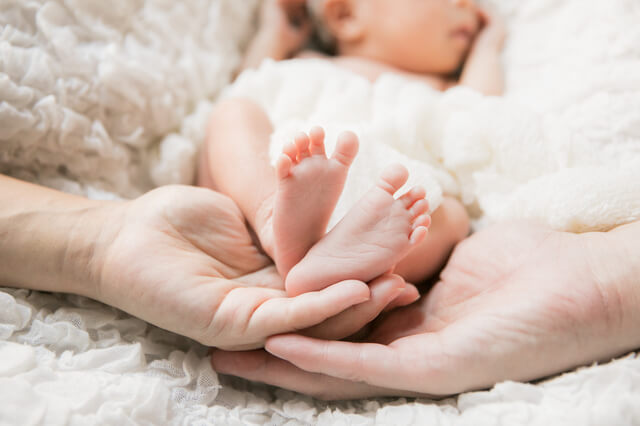 新生児の足に手を添える両親